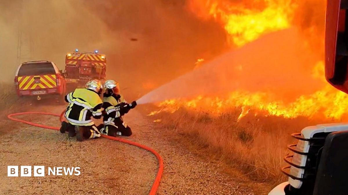 Firefighters work as flames and smoke rise during a wildfire, amid drought conditions following a heatwave and water