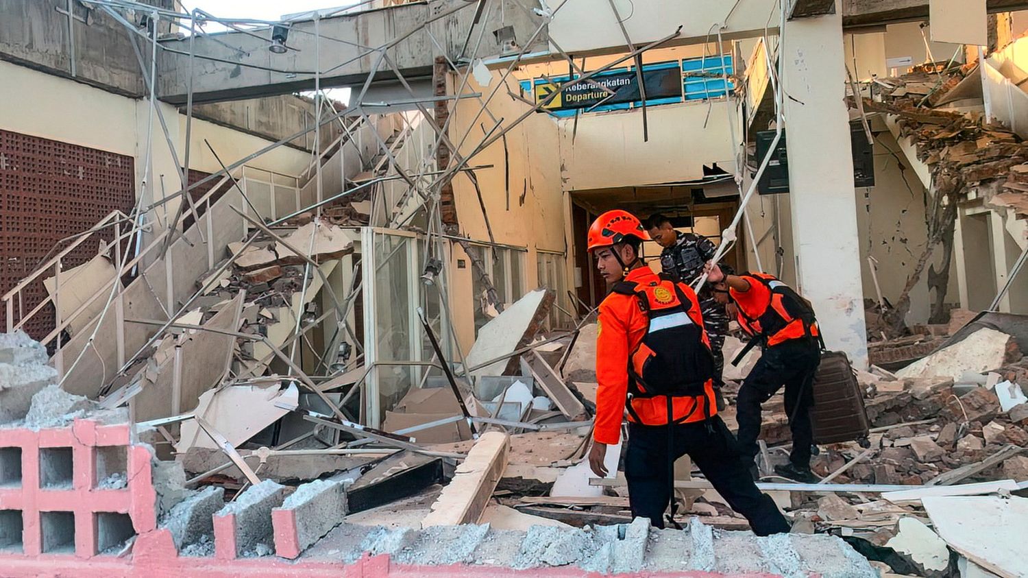 Des secouristes s'affairent dans les ruines d'un bâtiment après un puissant séisme à Maumere, en Indonésie, le 15 août 2026