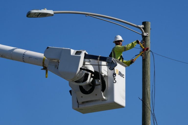 An electrical worker repairs power lines along a street in Gary, Ind, Thursday, Aug. 20, 2026, more than a week after a