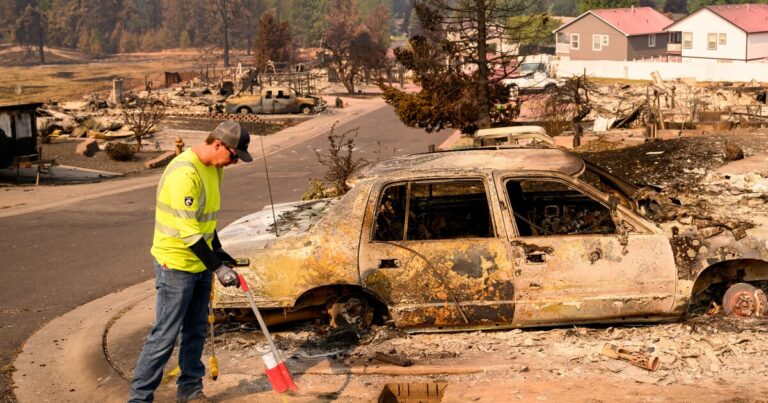 A utility worker marks a spot where a suspected gas line is at a burned property during the Old Trails fire in Spokane