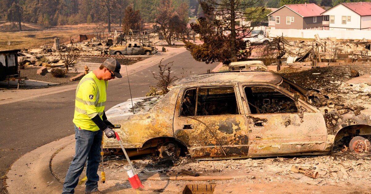 A utility worker marks a spot where a suspected gas line is at a burned property during the Old Trails fire in Spokane