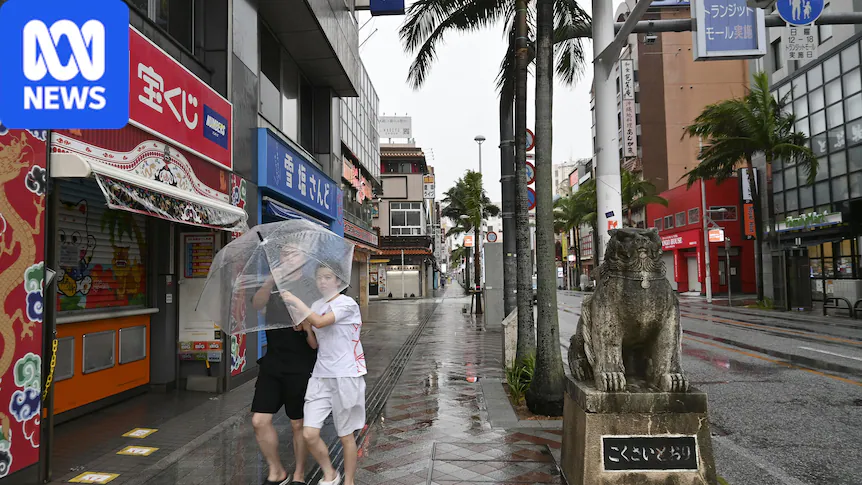 Two people share an umbrella on a rainy city street