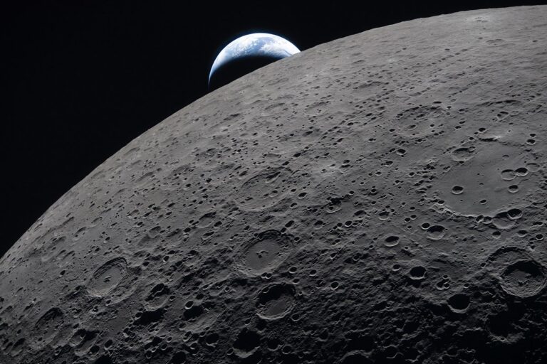 The crescent Earth sets against the shadowy, cratered limb of the moon