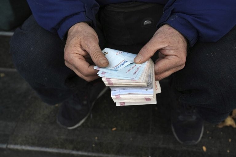 A street money exchanger poses for a photo without showing his face as he counts Iranian banknotes at a commercial district