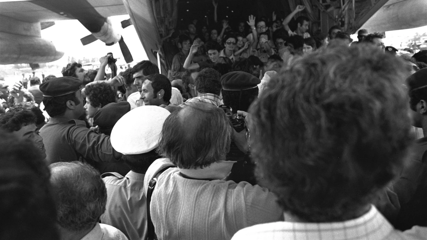 Rescued Air France passengers wave to the waiting crowd while leaving the belly of an IAF Hercules military transport