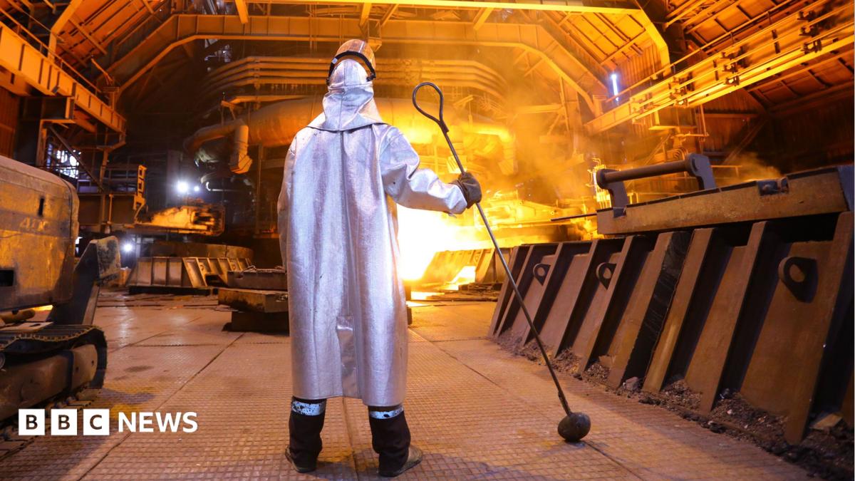 A man in a silver cloak stands near a blazing furnace holding a metal prod